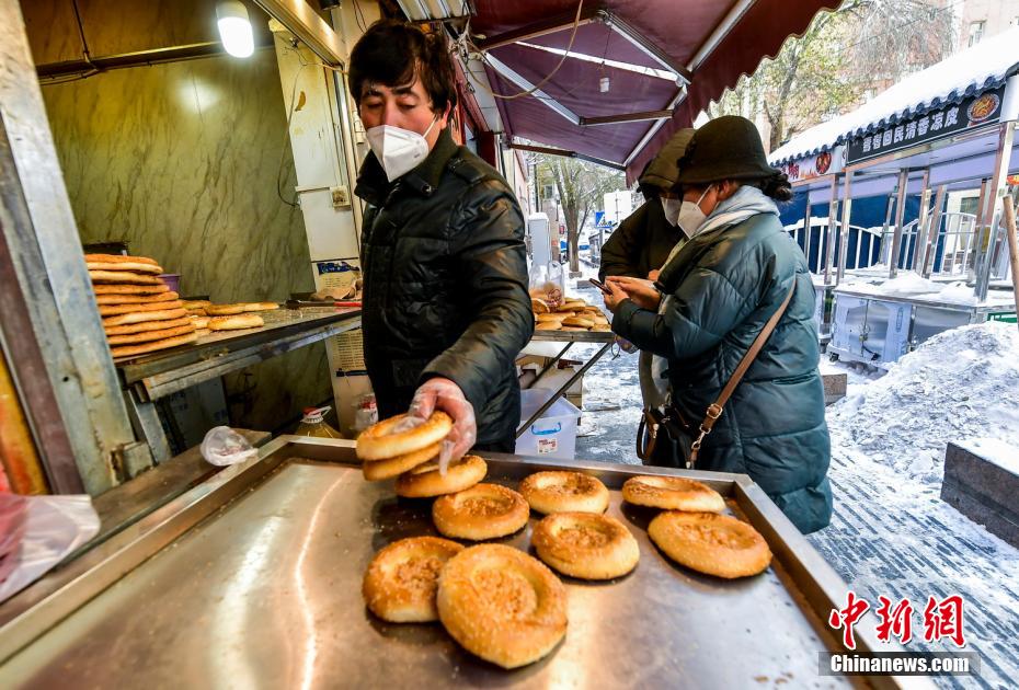 乌鲁木齐市文化路，已开门营业的馕店吸引过往市民前来购买。 刘新 摄